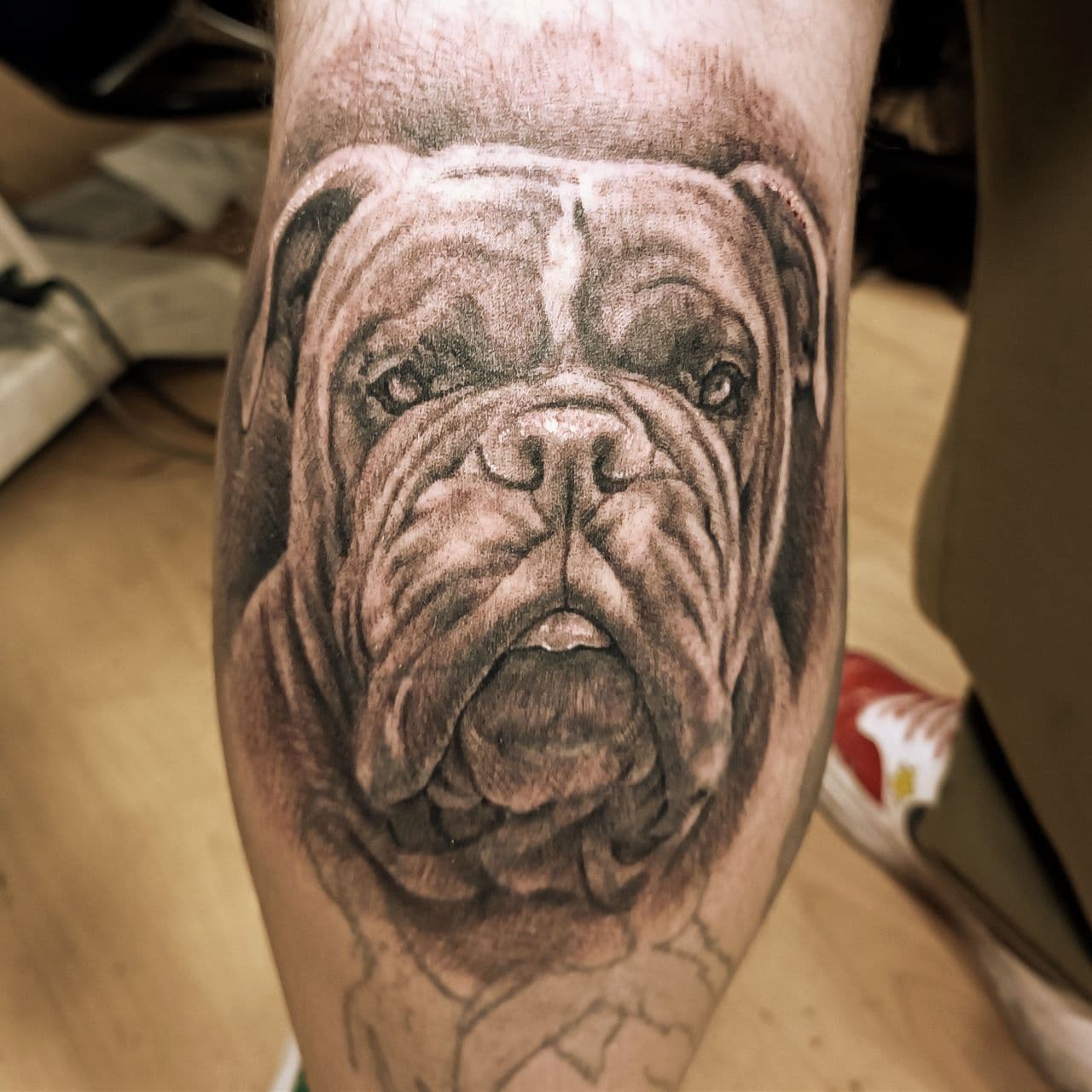 Black-and-grey tattoo – howling wolf in moonlight on the upper arm
